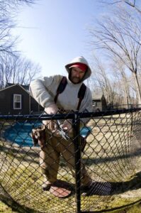 A man is repairing Chain Link Fence